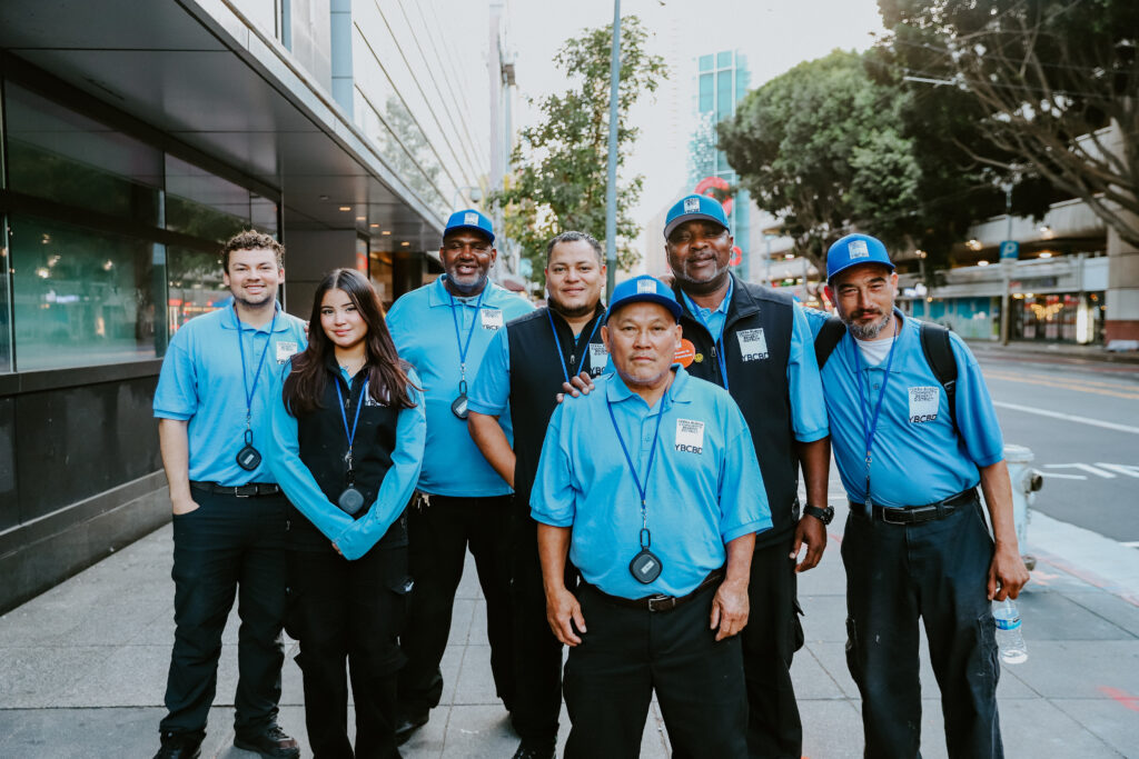 A group of Yerba Buena CBD Ambassadors pose for a photo while wearing matching uniforms on a downtown sidewalk.