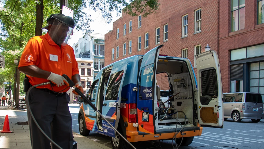 A man in an orange shirt holds a pressure washer in front of an LDP branded van.