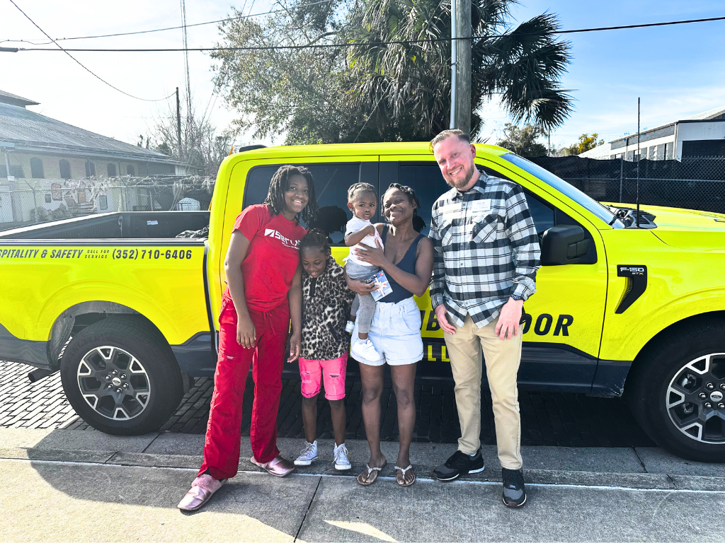 A family stands beside an outreach worker, in front of a branded vehicle for Gainesville.