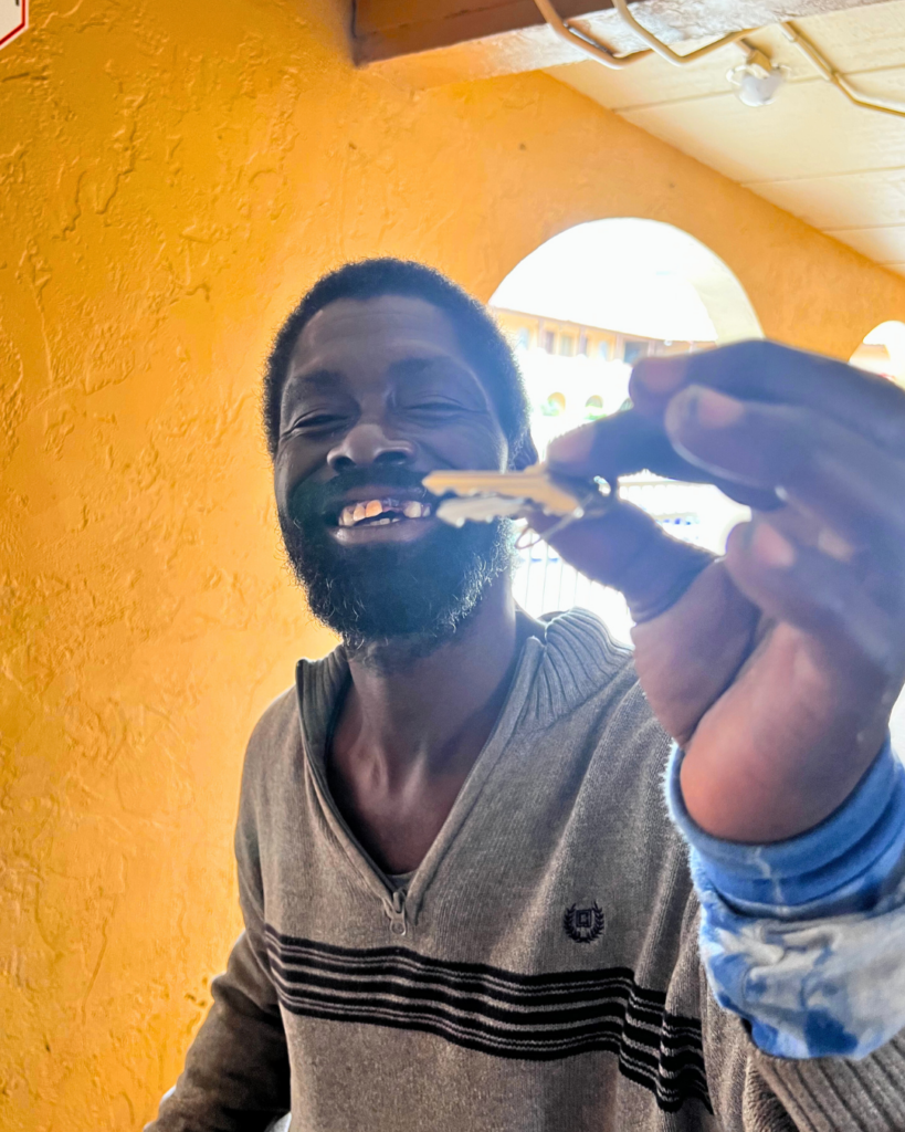 A man smiles as he holds up a set of keys.