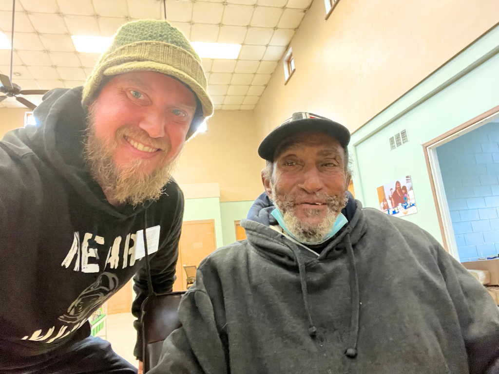 Outreach worker Eric smiles in a selfie alongside Vietnam Veteran Gary.